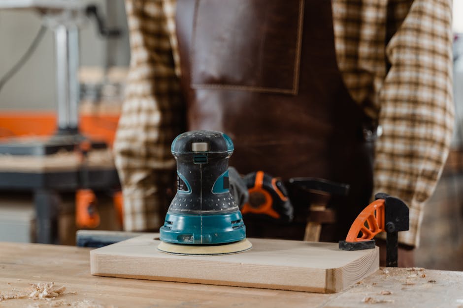 A skilled carpenter working with an electric sander on a wooden piece in a workshop.