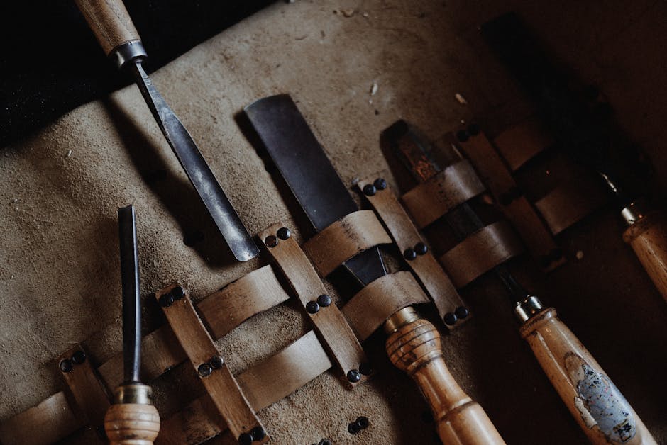Set of vintage woodworking chisels neatly arranged on a rustic leather mat, showcasing craftsmanship.