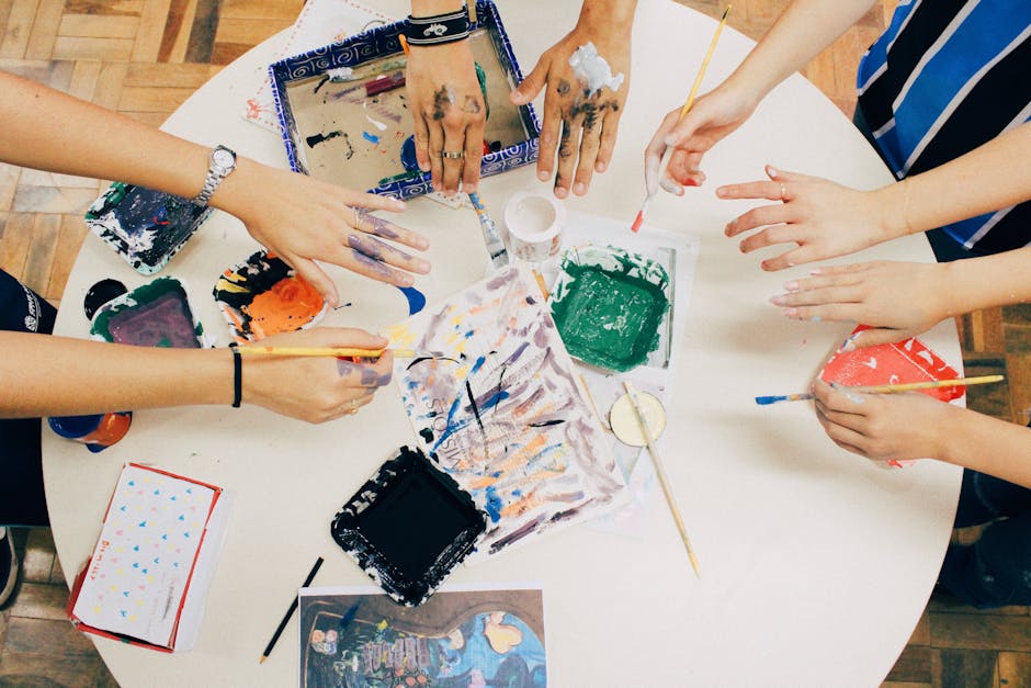 A group of people engaged in a creative painting session using mixed media on a round table.